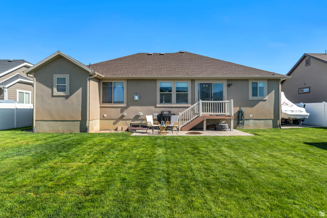 983 West 1550th Street South Springville, UT 84663 - Photo 43 of 43 Spacious backyard featuring a manicured lawn, an elevated deck with white railings, a ground-level concrete patio, and a stucco exterior
