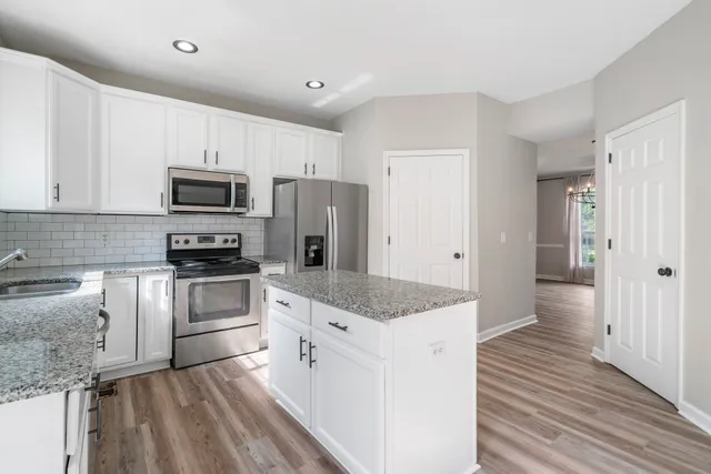 a kitchen with granite countertop a sink stove and refrigerator