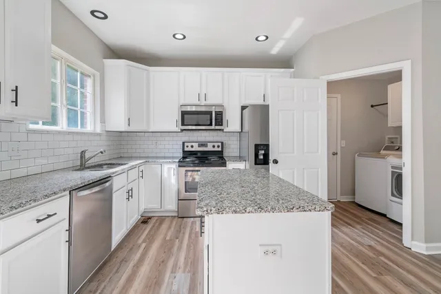a kitchen with kitchen island granite countertop a sink refrigerator and cabinets