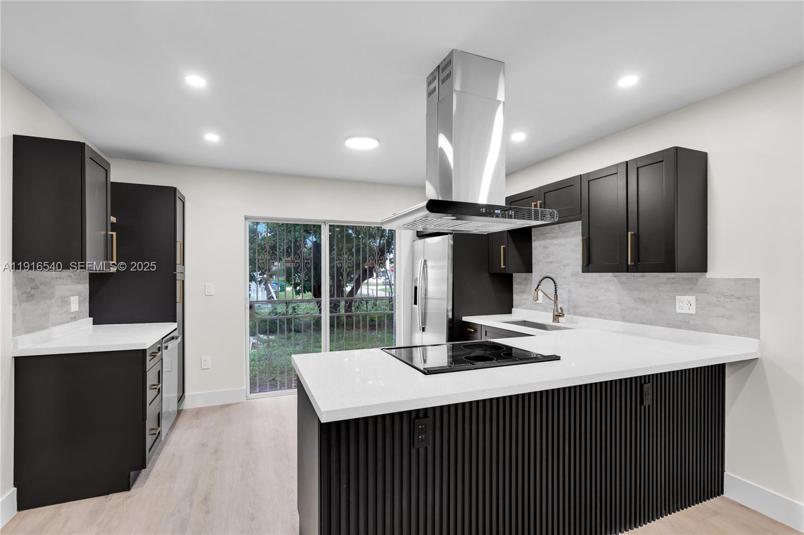 1253 Northwest 44th Street Miami, FL 33142 - Photo 4 of 25 a kitchen with kitchen island granite countertop a sink stainless steel appliances and cabinets