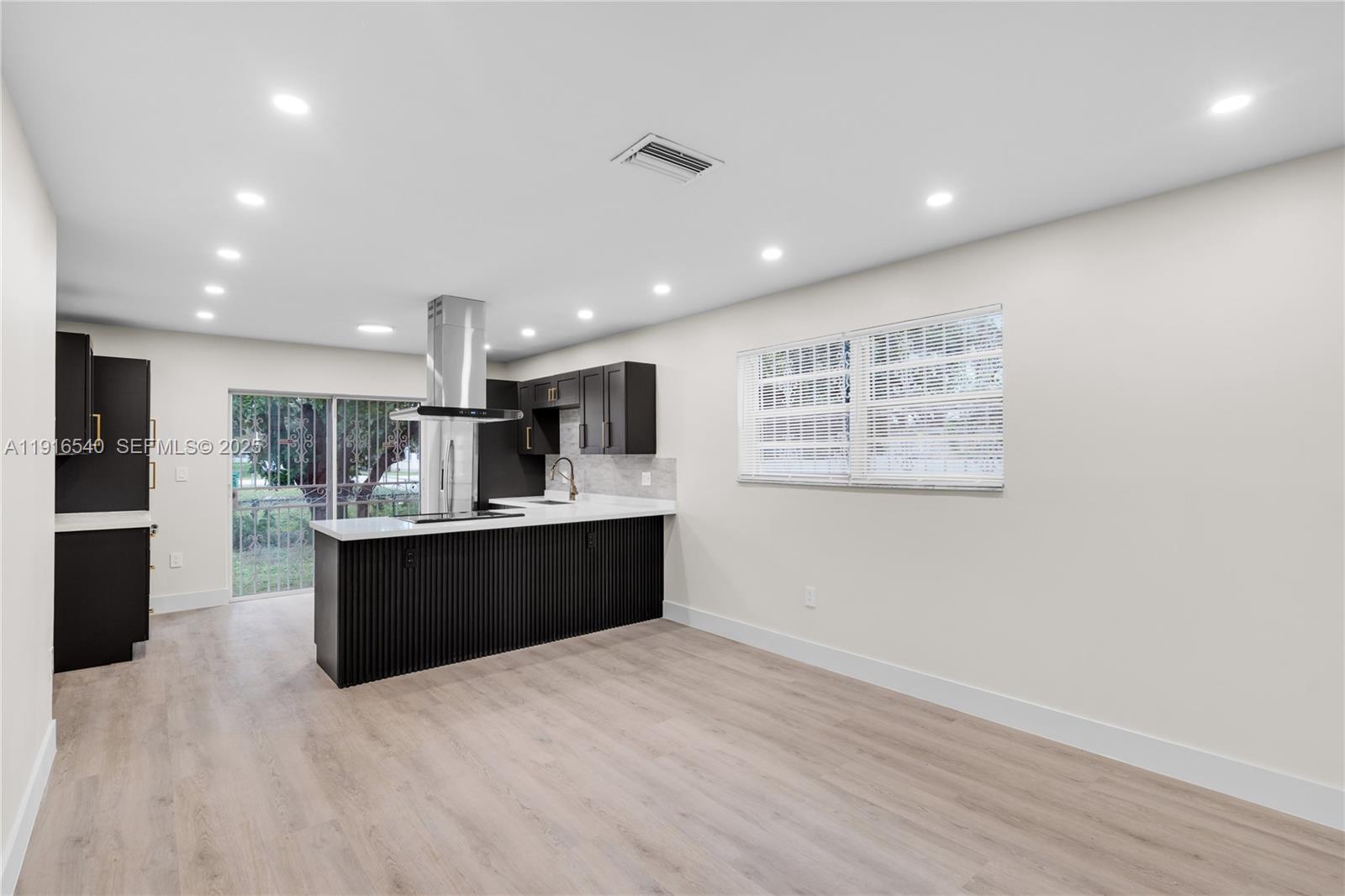 1253 Northwest 44th Street Miami, FL 33142 - Photo 6 of 25 a large kitchen with stainless steel appliances kitchen island a large counter top and a wooden floor