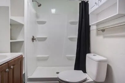 a white toilet sitting next to a bathroom sink and a shower
