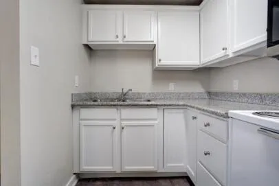 a kitchen with granite countertop white cabinets and a sink