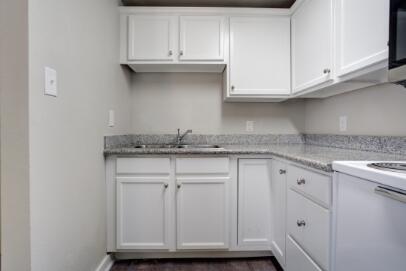 2305 14th Street, Unit B Lubbock, TX 79401 - Photo 6 of 14 a kitchen with granite countertop white cabinets and a sink