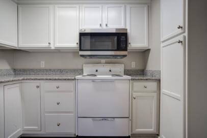2305 14th Street, Unit B Lubbock, TX 79401 - Photo 7 of 14 a kitchen with granite countertop white cabinets and a sink