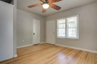 a view of an empty room with wooden floor and a window
