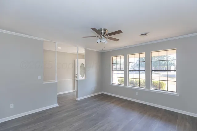 a view of an empty room with a window and wooden floor