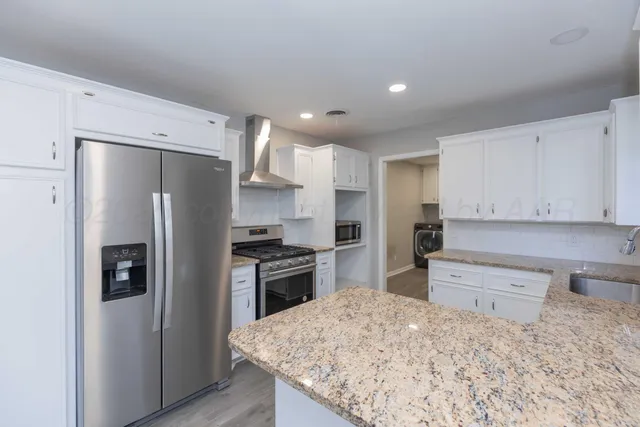 a kitchen with granite countertop a refrigerator and a stove top oven