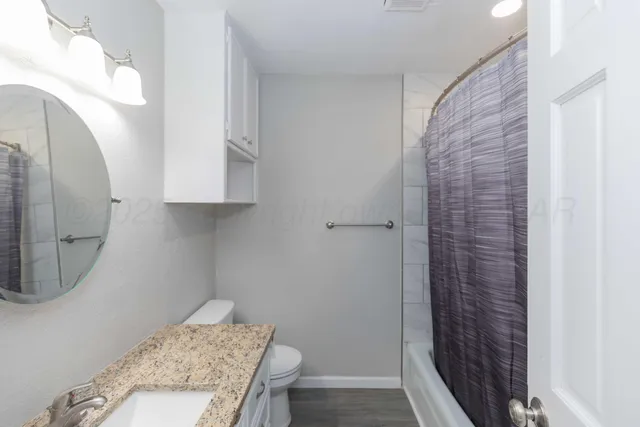 a bathroom with a granite countertop shower a sink and a toilet