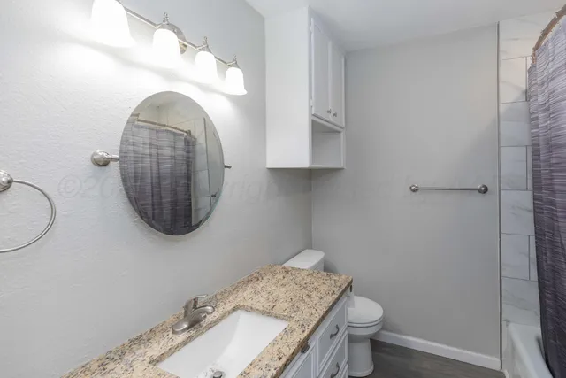 a bathroom with a granite countertop toilet a sink and a mirror