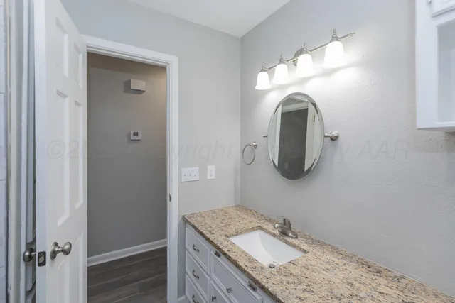 a bathroom with a granite countertop sink and a mirror