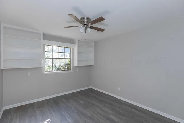 an empty room with wooden floor fan and windows