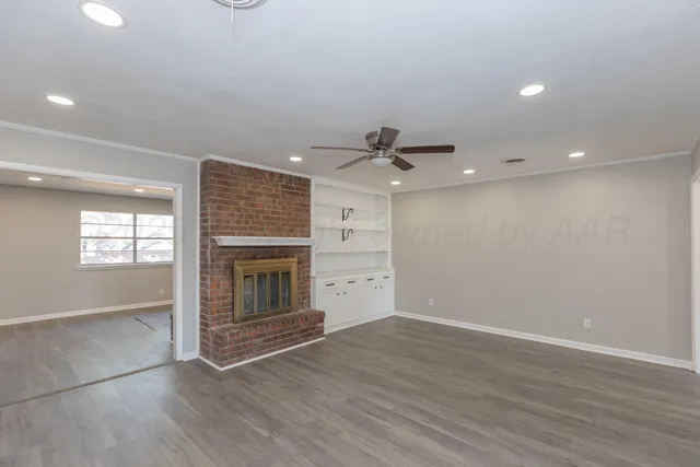 an empty room with wooden floor fireplace and windows