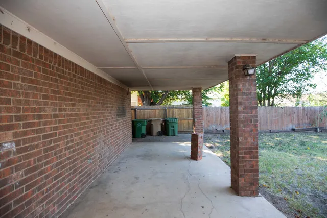 a view of a patio with a table and chairs under an umbrella with a small yard