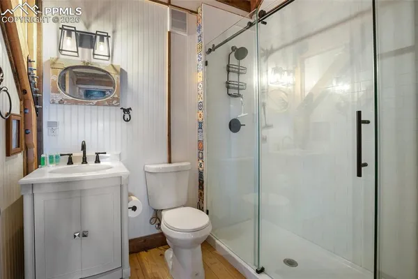 a bathroom with a granite countertop sink a mirror a toilet and shower