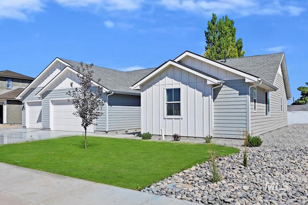 View of front of house featuring board and batten siding, a front lawn, a garage, and a shingled roof