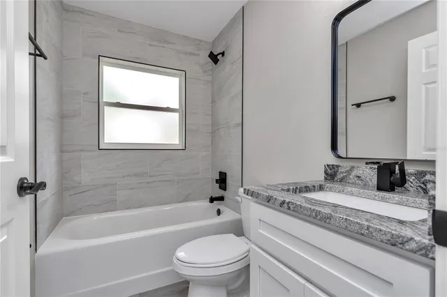 a bathroom with a granite countertop toilet a sink and a bathtub