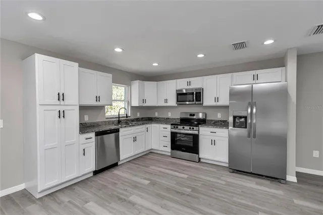 a large kitchen with stainless steel appliances granite countertop a stove a sink and a refrigerator