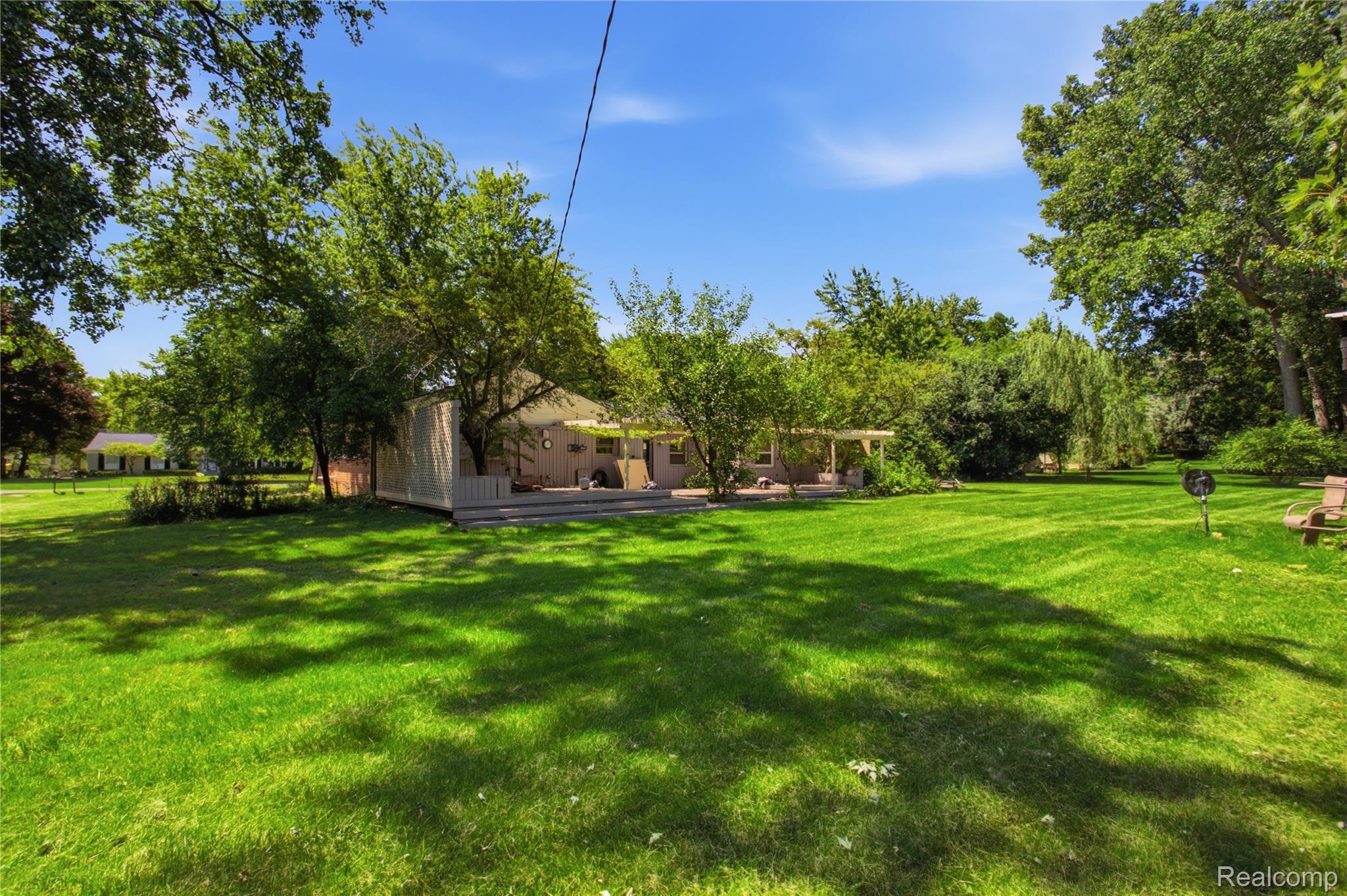 3812 Terrybrook Road West Bloomfield, MI 48322 - Photo 35 of 43 Spacious backyard featuring a large green lawn, mature trees, and a multi-level wooden deck
