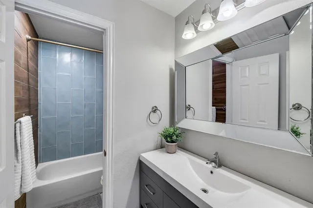 a bathroom with a bathtub shower sink and mirror