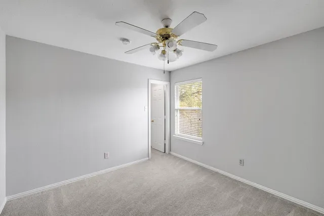 an empty room with window and ceiling fan