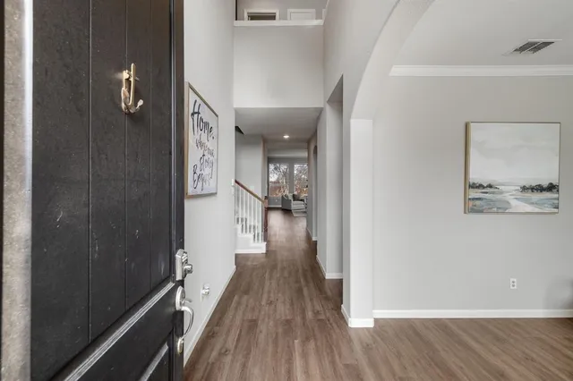 a view of a hallway with wooden floor and a bathroom