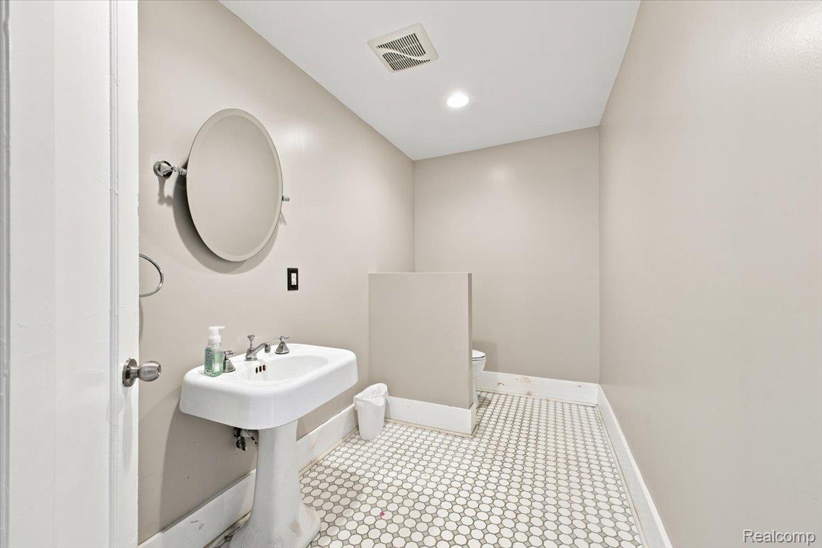 899 Edison Street Detroit, MI 48202 - Photo 27 of 37 Pedestal sink with chrome fixtures, oval mirror, recessed lighting, and hex tile flooring