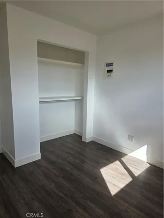 an empty room with wooden floor & closet