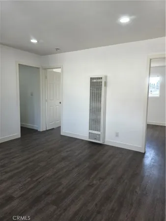 a view of an empty room with wooden floor and closet