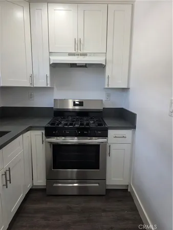a kitchen with granite countertop white cabinets and stainless steel appliances