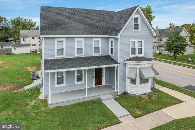 a view of a yard in front of a house with plants and large tree