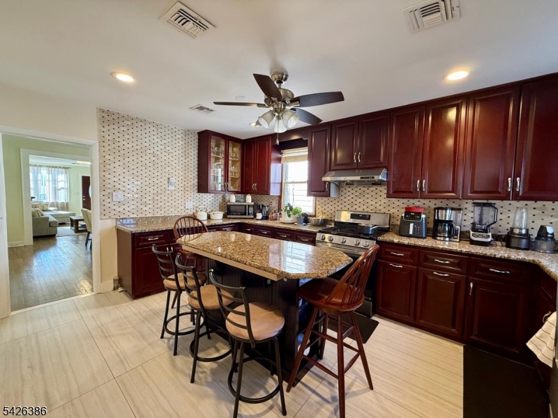 195 Maple Street Kearny, NJ 07032 - Photo 3 of 24 a kitchen with stainless steel appliances granite countertop wooden floors a stove a sink and a refrigerator