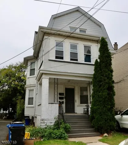 a view of a white house with potted plants and a table and chairs