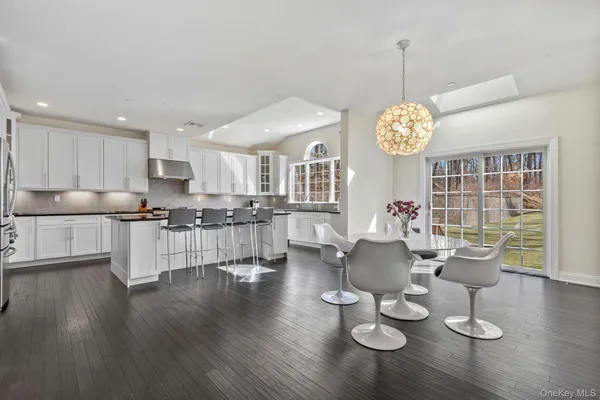 a dining room with wooden floor a chandelier a glass table and chairs