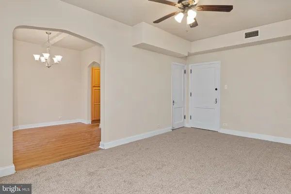 a view of an empty room with a chandelier fan