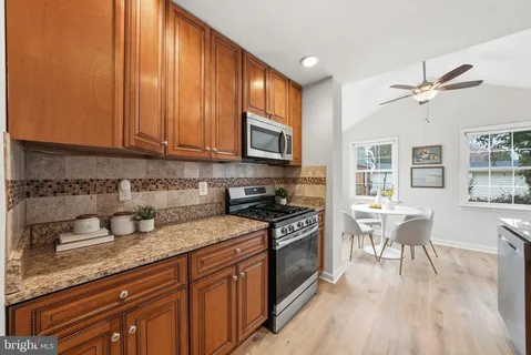 a kitchen with granite countertop wooden floors stainless steel appliances a sink and cabinets