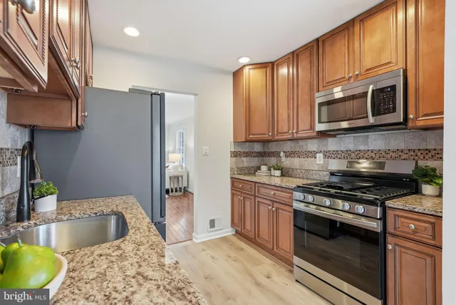 a kitchen with stainless steel appliances granite countertop a stove a sink and a microwave