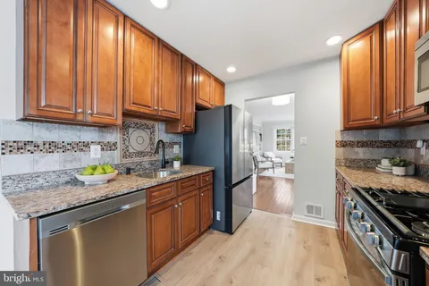 a kitchen with stainless steel appliances granite countertop a refrigerator a sink dishwasher stove and countertops with wooden cabinets