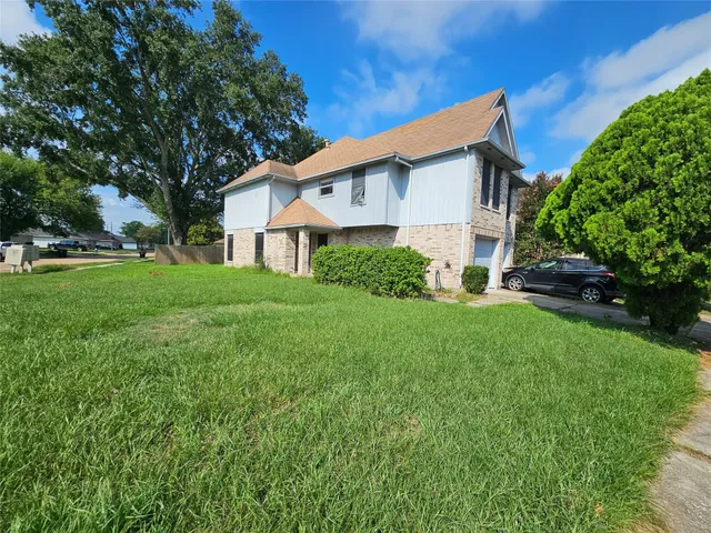 a view of a house with a big yard plants and large trees