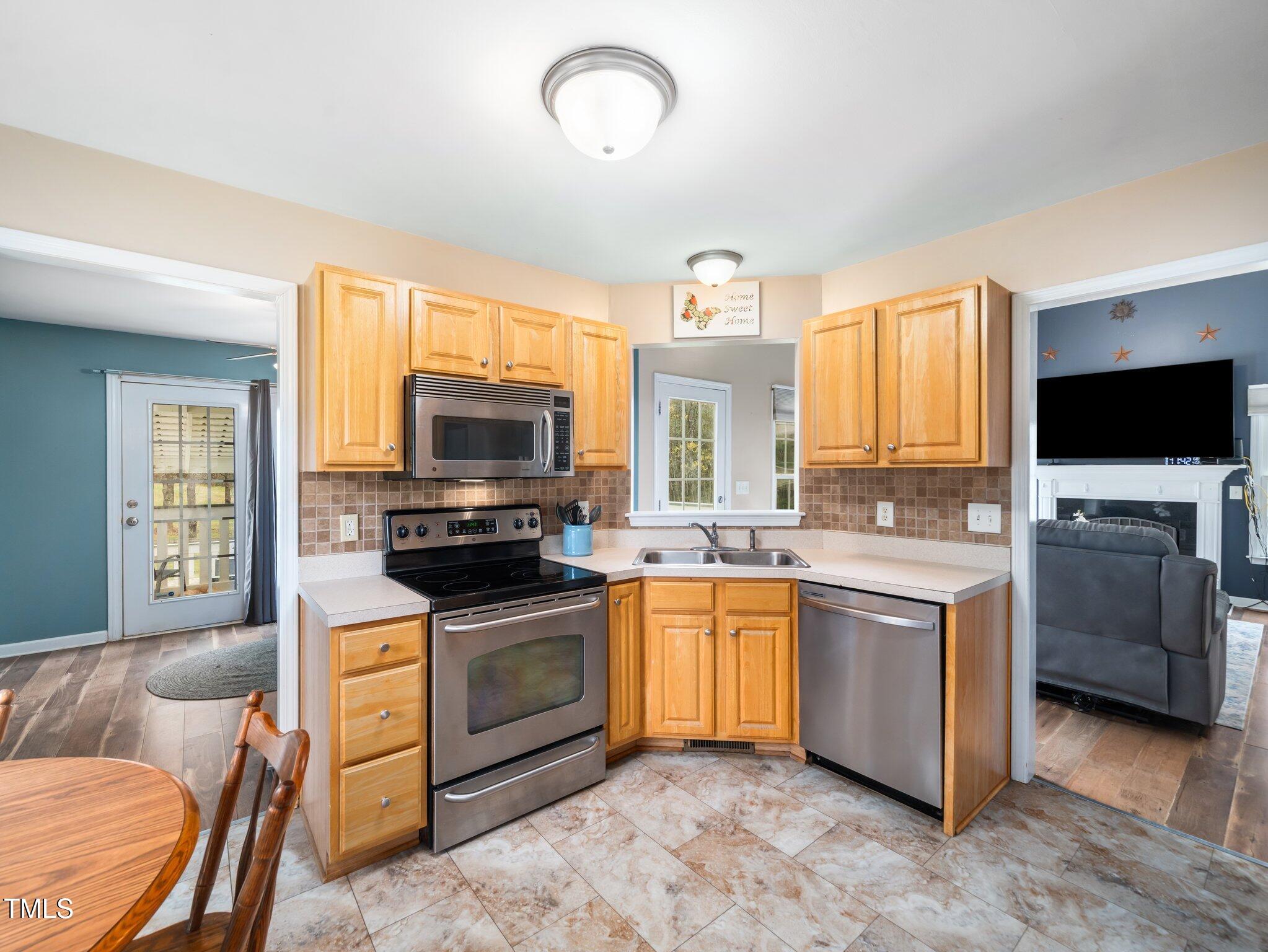 3690 Mabel Lane Stem, NC 27581 - Photo 9 of 37 a kitchen with stainless steel appliances granite countertop a stove top oven a sink dishwasher a dining table and chairs with wooden floor