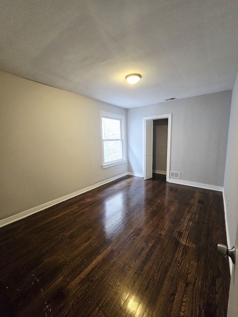 4819 West George Street, Unit 2 Chicago, IL 60641 - Photo 3 of 9 a view of an empty room with wooden floor and a window