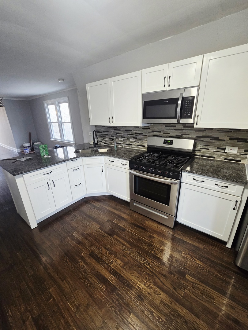 4819 West George Street, Unit 2 Chicago, IL 60641 - Photo 7 of 9 a kitchen with granite countertop a stove and a sink
