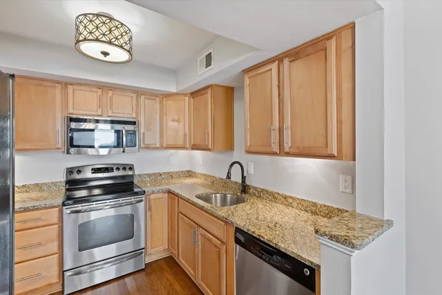 a kitchen with stainless steel appliances granite countertop a sink a stove and cabinets