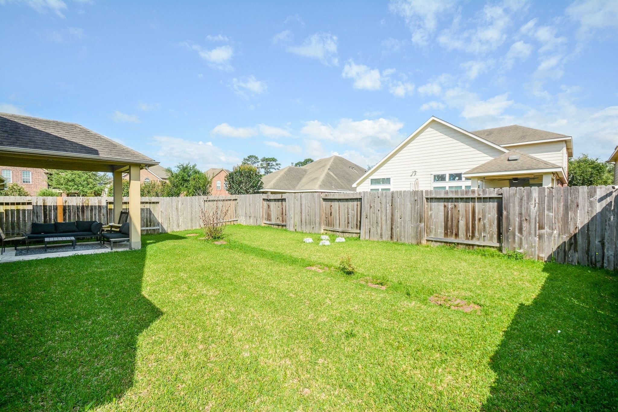 7046 Sliding Rock Circle Spring, TX 77379 - Photo 34 of 41 Spacious backyard with lush green lawn, perfect for relaxation and outdoor gatherings. Enjoy the privacy of a fenced-in area and a cozy covered seating space.