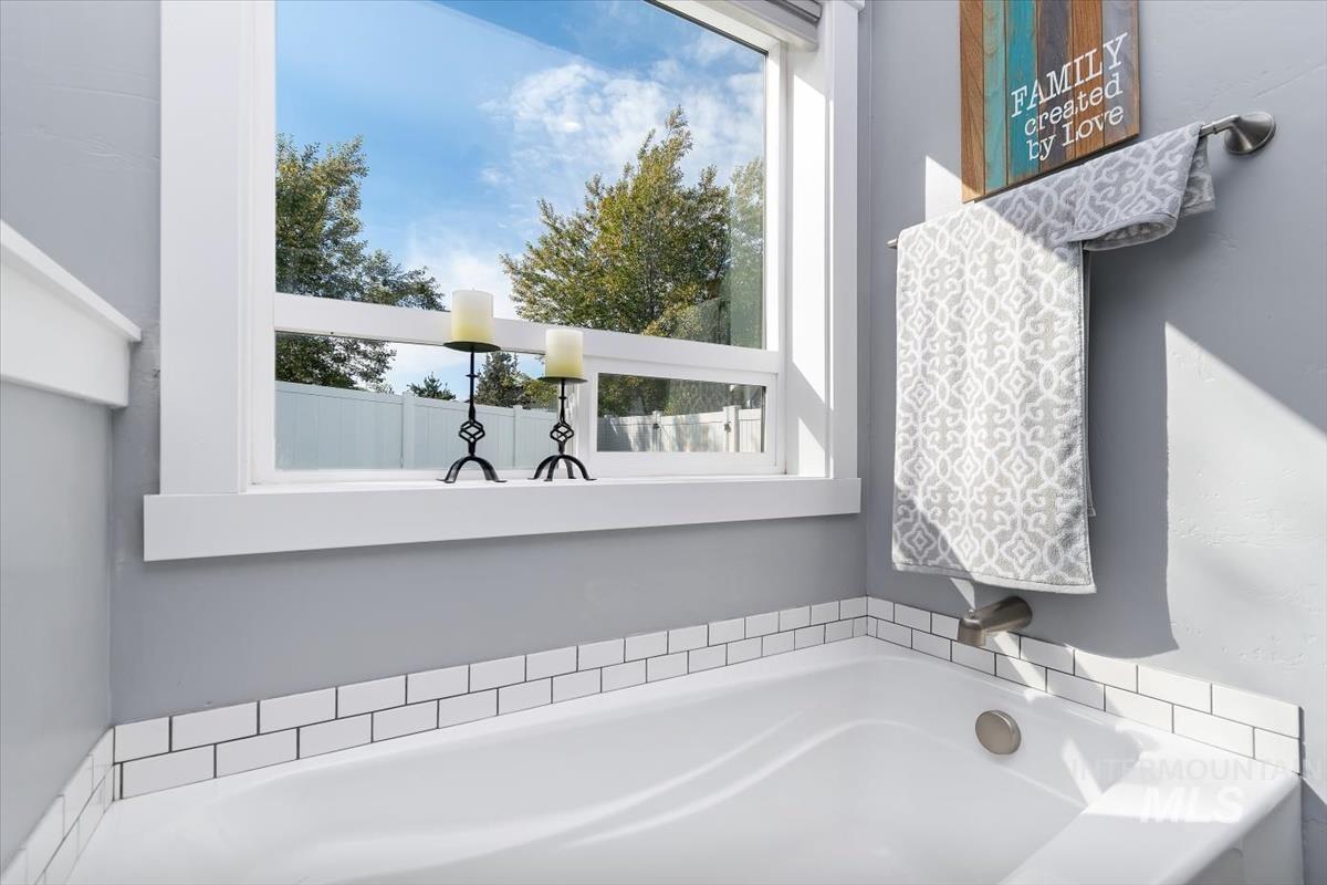 15015 Leon Lane Caldwell, ID 83607 - Photo 23 of 44 Soaking tub with subway tile surround, brushed nickel fixtures, and a window with white trim