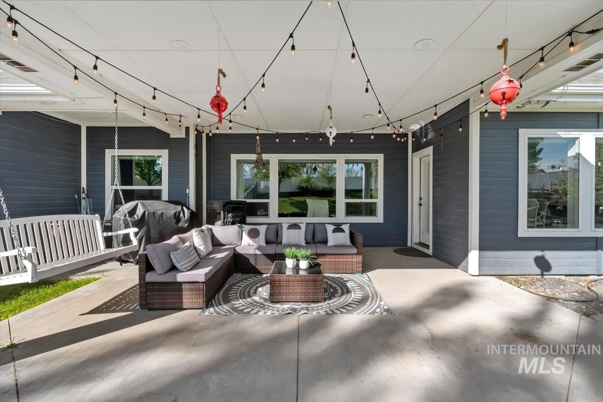 15015 Leon Lane Caldwell, ID 83607 - Photo 30 of 44 Covered patio featuring a concrete surface, white porch swing, and dark gray siding