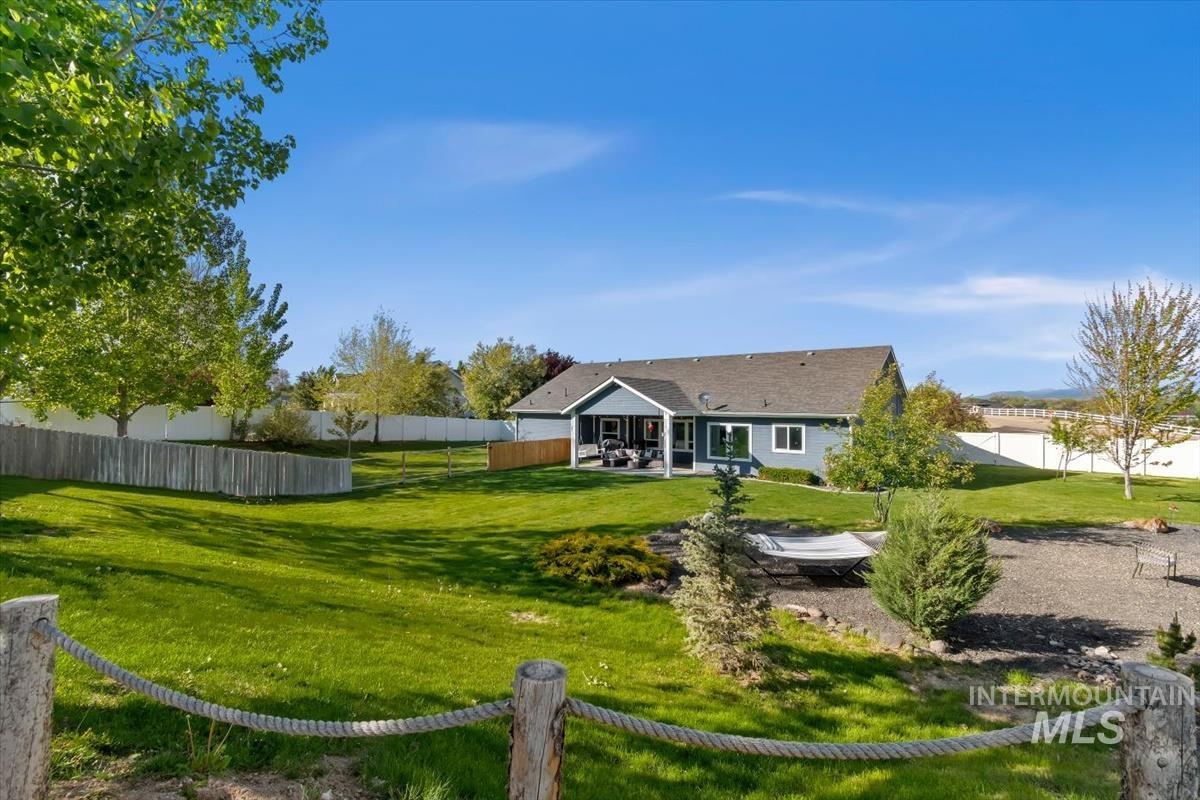 15015 Leon Lane Caldwell, ID 83607 - Photo 33 of 44 Expansive backyard featuring a manicured lawn and mature trees, partial privacy fencing, and a gravel entertainment area