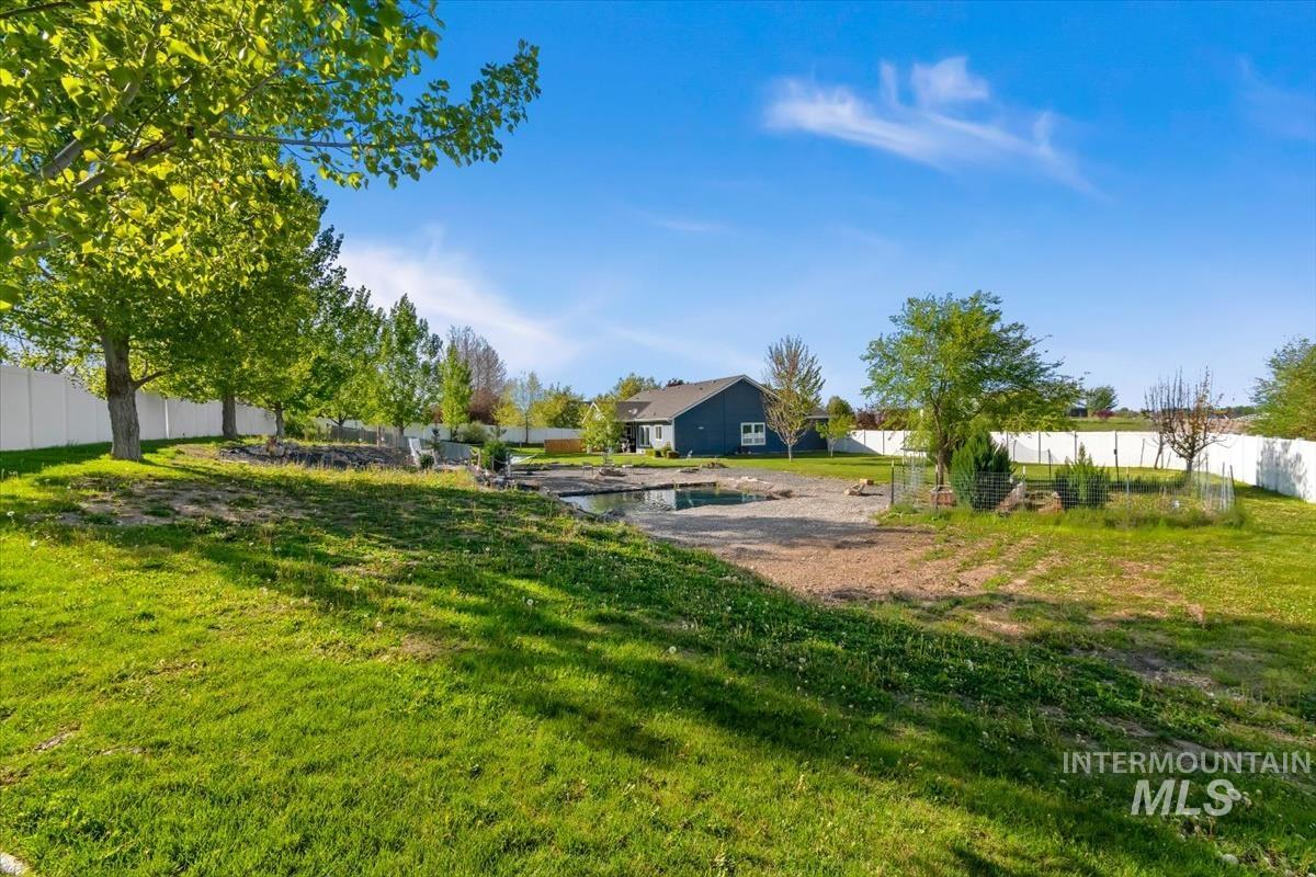 15015 Leon Lane Caldwell, ID 83607 - Photo 35 of 44 Expansive backyard featuring a manicured lawn, established trees, and a white vinyl privacy fence