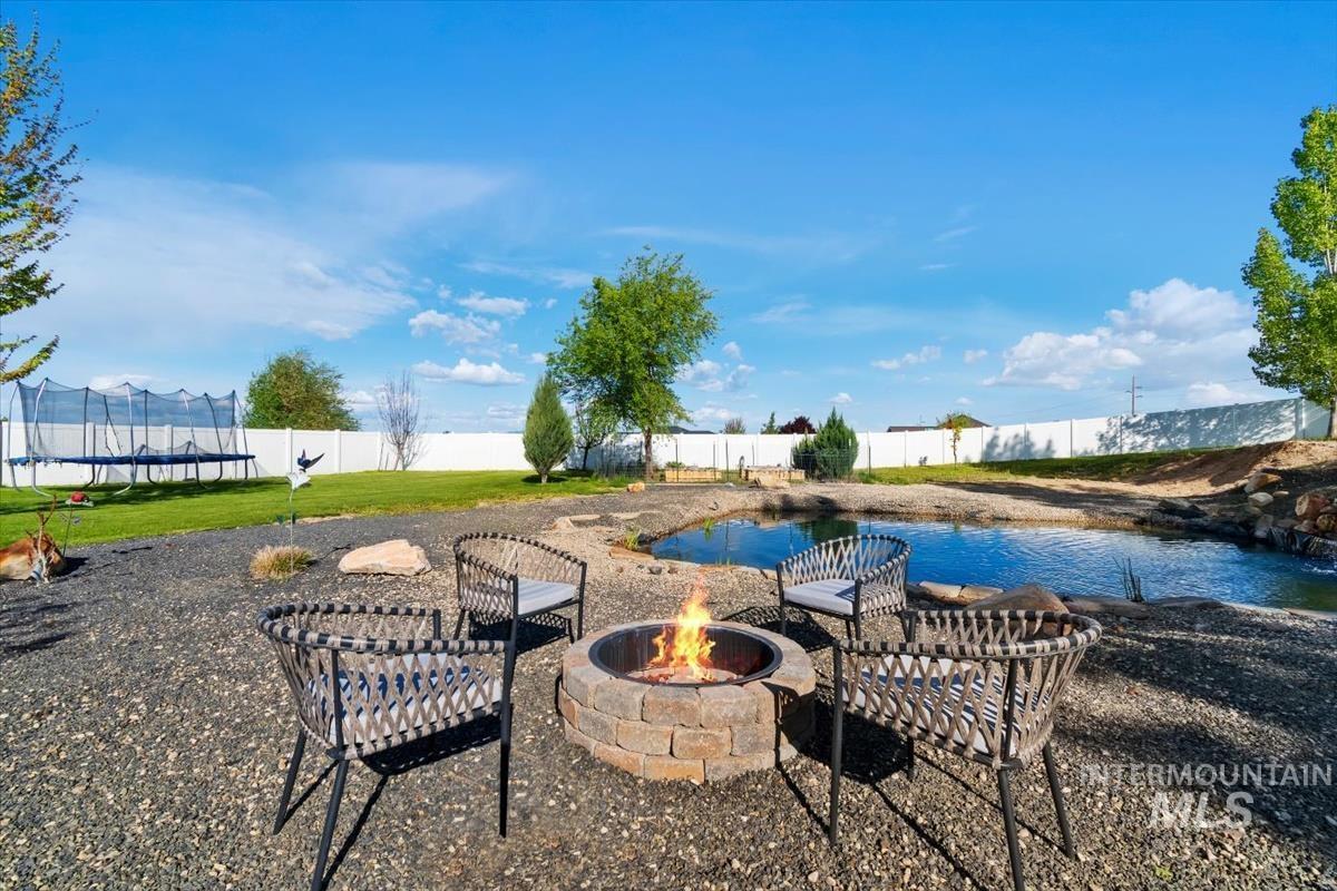 15015 Leon Lane Caldwell, ID 83607 - Photo 36 of 44 Expansive backyard featuring a stone-clad fire pit, surrounded by gravel landscaping and a natural pond