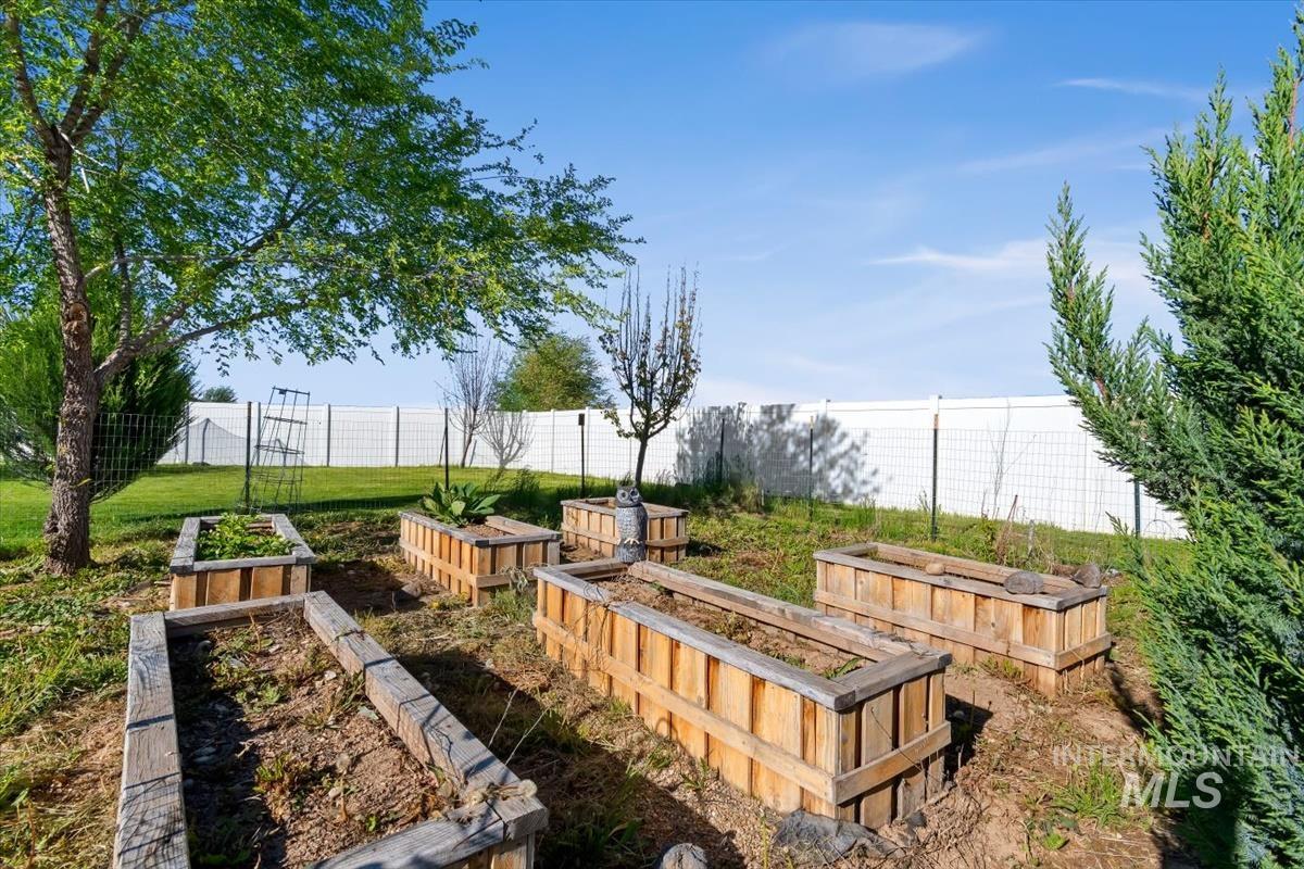 15015 Leon Lane Caldwell, ID 83607 - Photo 37 of 44 Garden area featuring multiple raised wooden planter boxes, established landscaping, and a perimeter fence